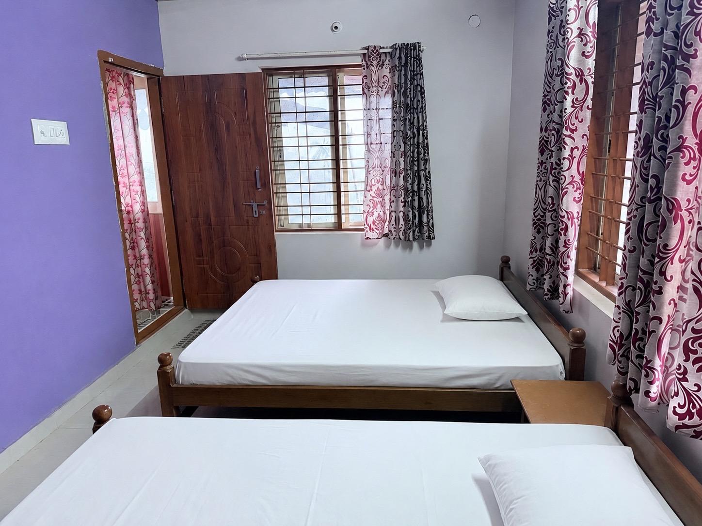 Two-bed room with bright windows and view of the greenery outside